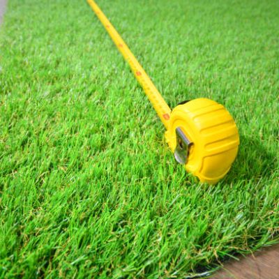 Artificial grass and measure tape lie on the laminate floor